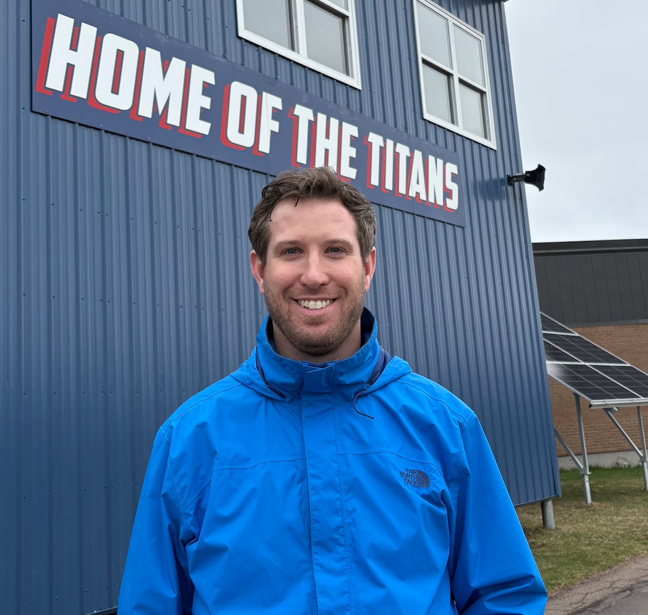 A smiling man wearing a blue rain coat.