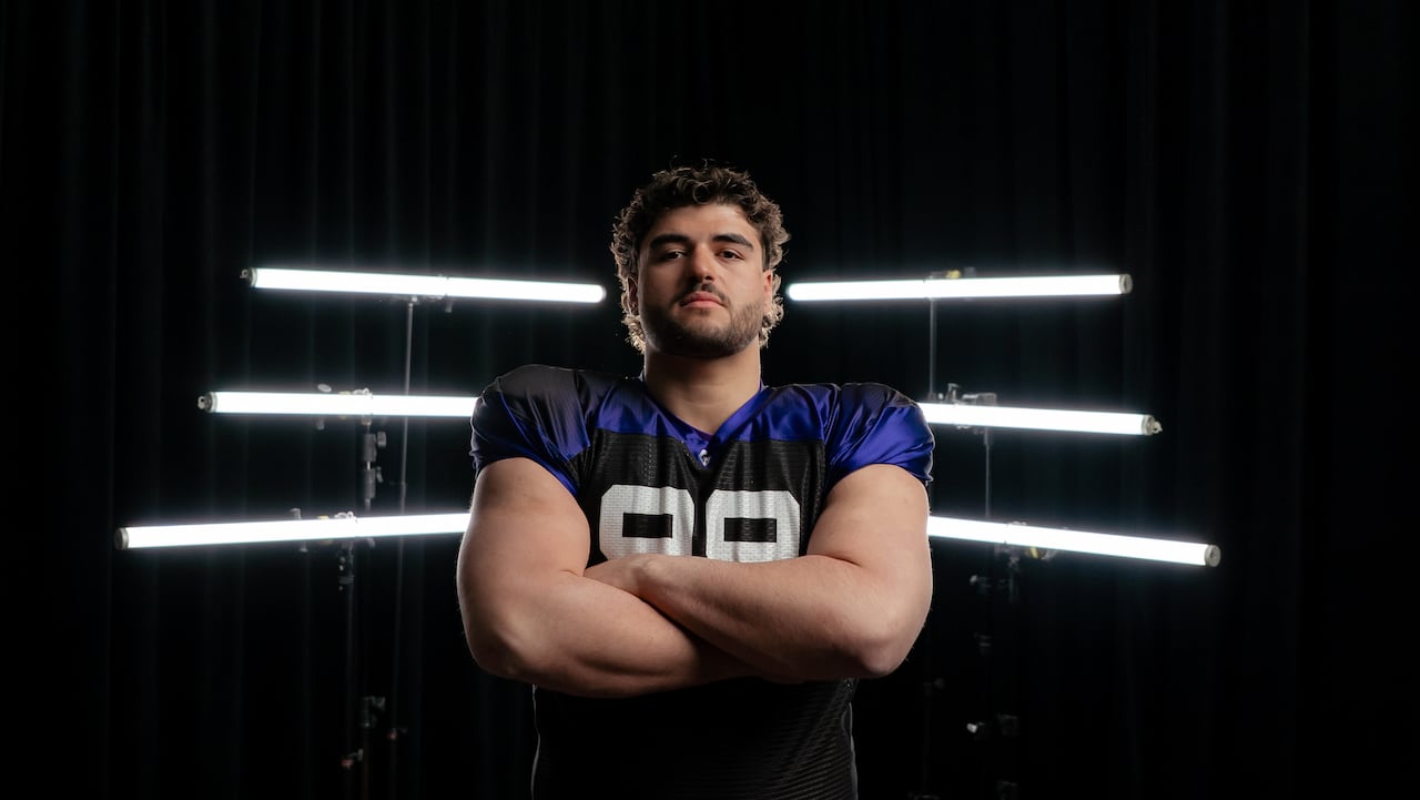 A football player poses with his arms crossed in front of his chest.