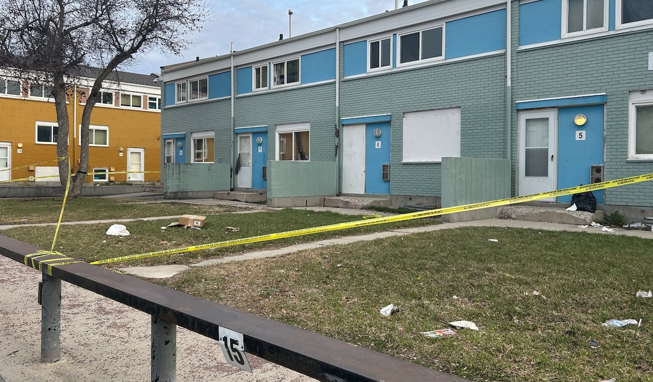 Yellow police tape stretches across several front yards of an apartment complex.