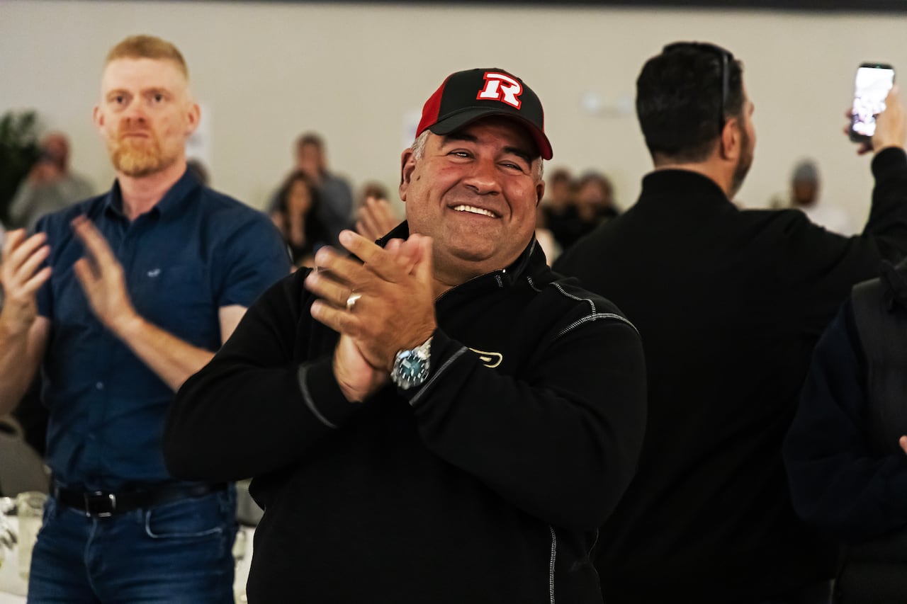 A man wearing a Redblacks clap smiling and clapping.