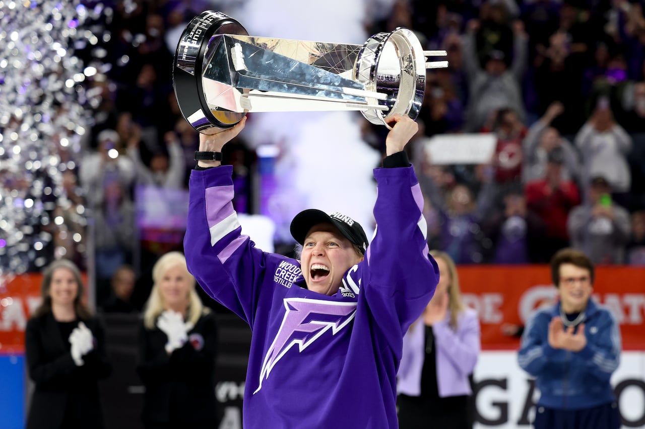 A hockey player lifts a championship trophy.