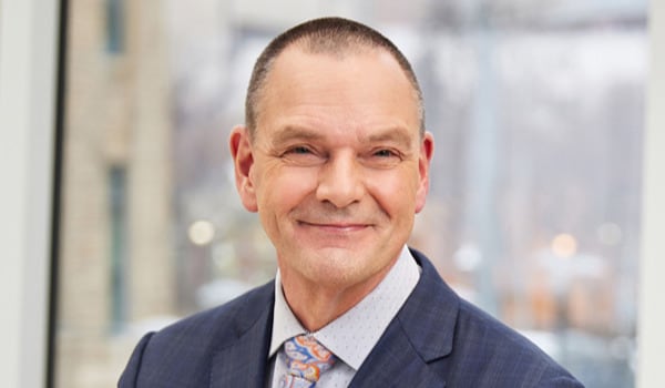 A smiling man dressed in a suit and tie.