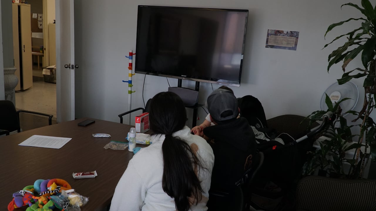 A woman, man and baby sit at a conference table with baby toys.