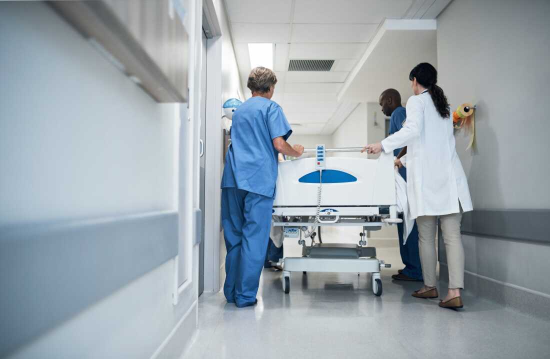 Rearview shot of a medical team pushing a patient down the hallway in a gurney