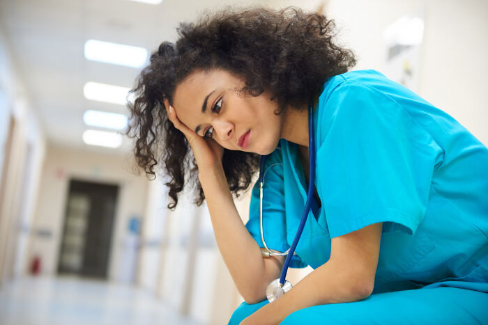 Tired nurse in hospital hallway, reflecting the hidden truths about why many dislike hospitals and healthcare realities.