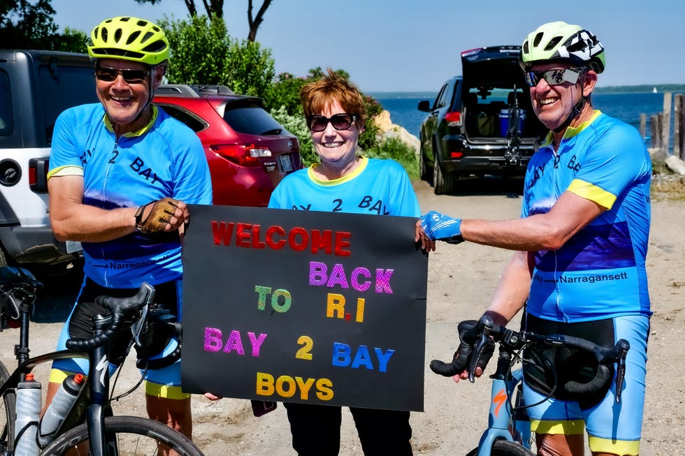 Group of cyclists holding a welcome sign at a scenic location. Group of cyclists holding a welcome sign at a scenic location.