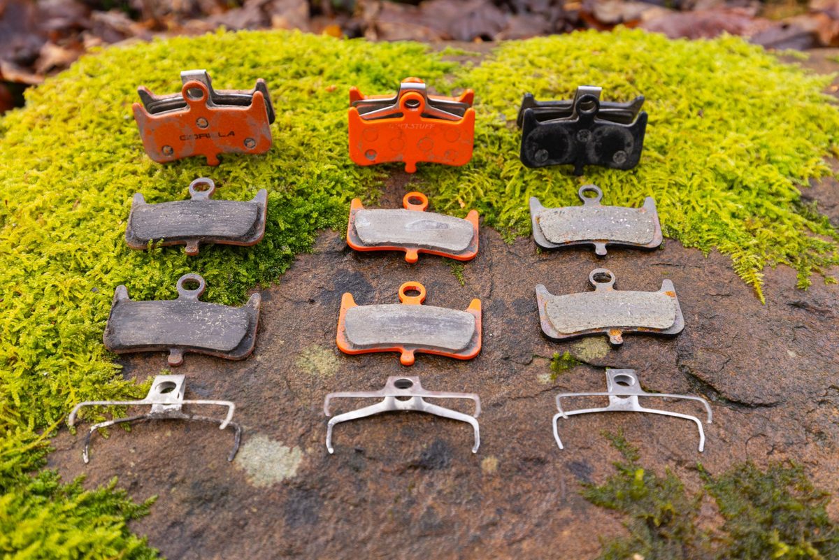 A pair of Gorillia Enduro Pro, Trickstuff Power, and AliExpress Kingstop brake pads lais out on a mossy rock.