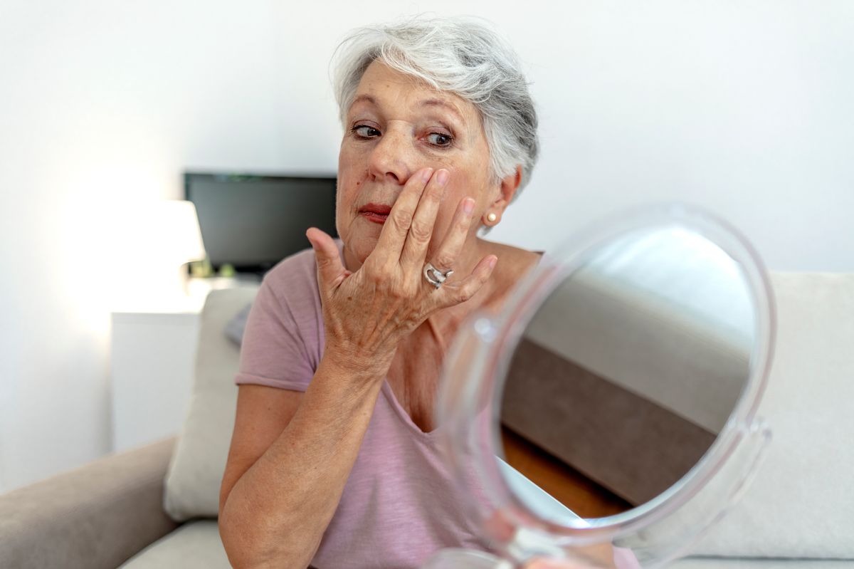 Woman looking at her face in the mirror