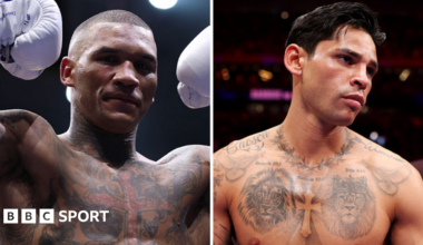 Conor Benn holds up his arms and stands next to Ryan Garcia