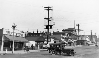 1925: The foot of Lonsdale Avenue, below Esplanade, featured the Sugar Bowl Restaurant, North Vancouver Cartage Co. Try Me Shoe Shop, Alexander Smith Real Estate and Anderson's Pharmacy.