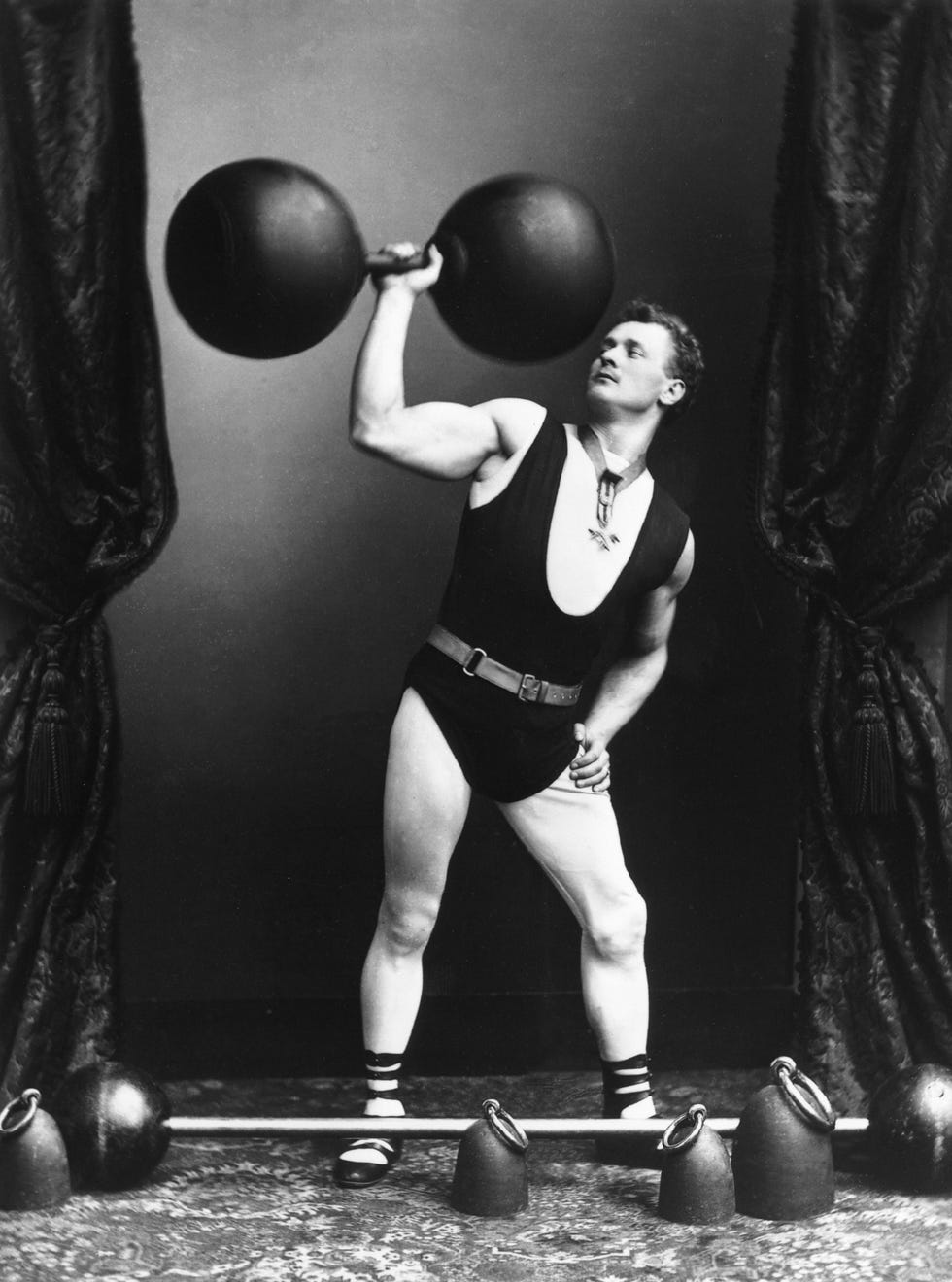 circa 1895: german strong man eugene sandow (1867 1925) lifting weights and dumbbells. (photo by rischgitz/getty images)