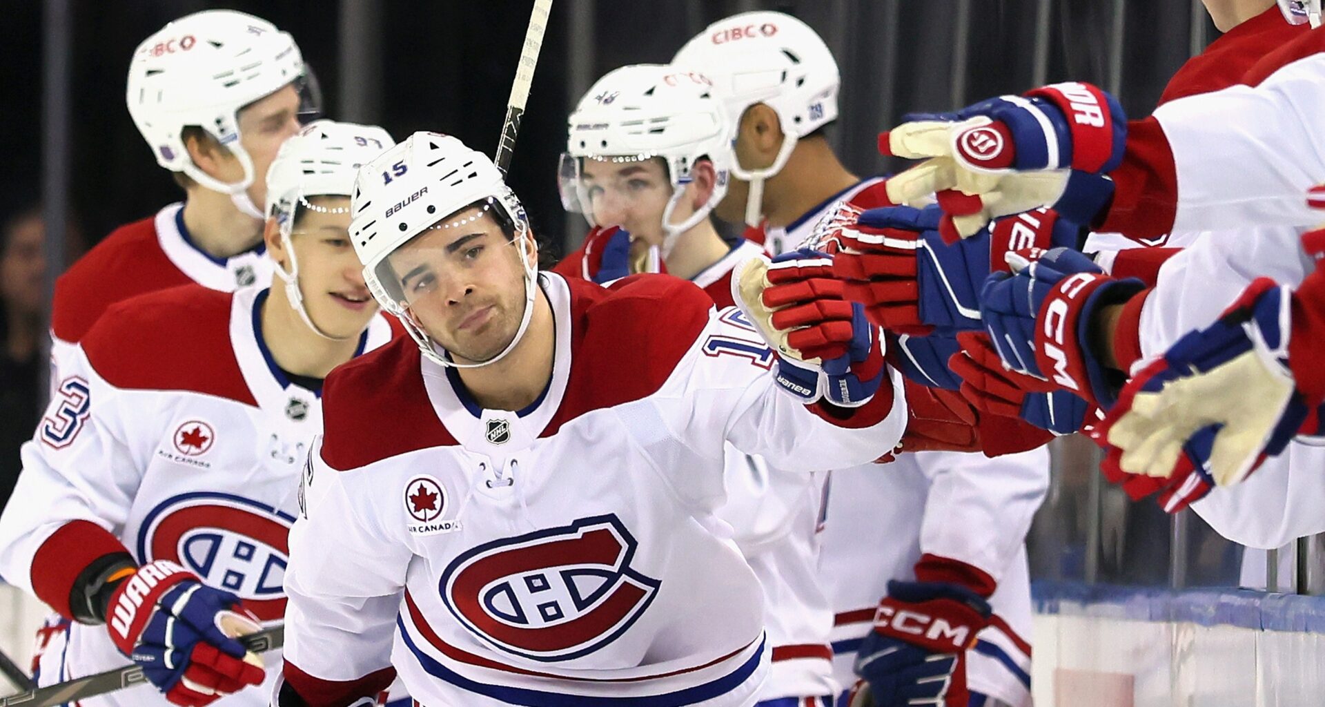 Hockey player skates along the bench to tap gloves with his teammates after scoring a goal.