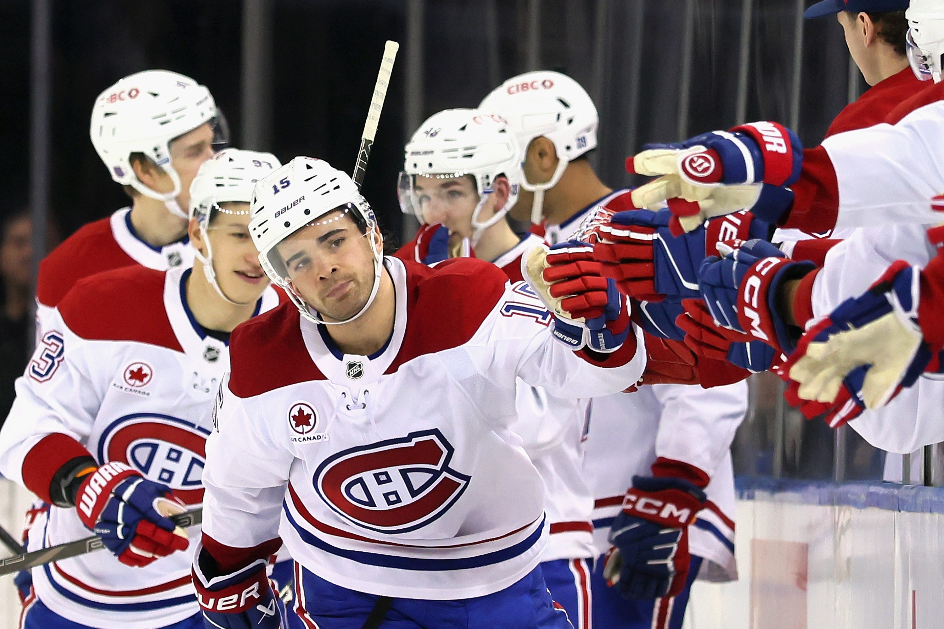 Hockey player skates along the bench to tap gloves with his teammates after scoring a goal.