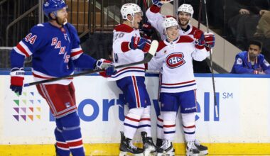 Hockey players gather to celebrate the winning goal as an opponent stands nearby looking dejected.