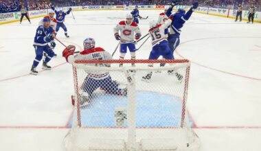 Tampa Bay Lightning players raise their arms in celebration as the puck is in the net behind the Canadiens goaltender, in a photo from behind the net.