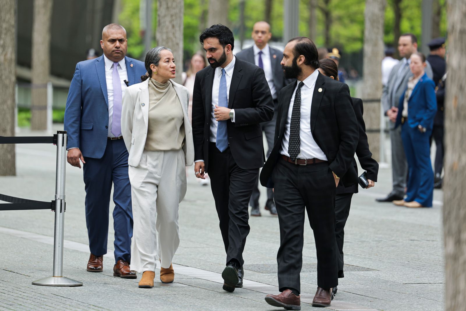Image may contain Person Walking People Clothing Pants Blazer Coat Jacket Formal Wear Suit Pedestrian and Adult