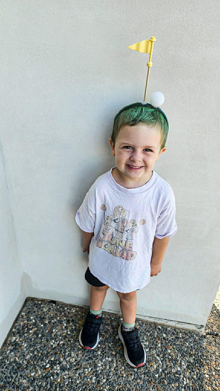 A young boy smiling wearing a golf costume