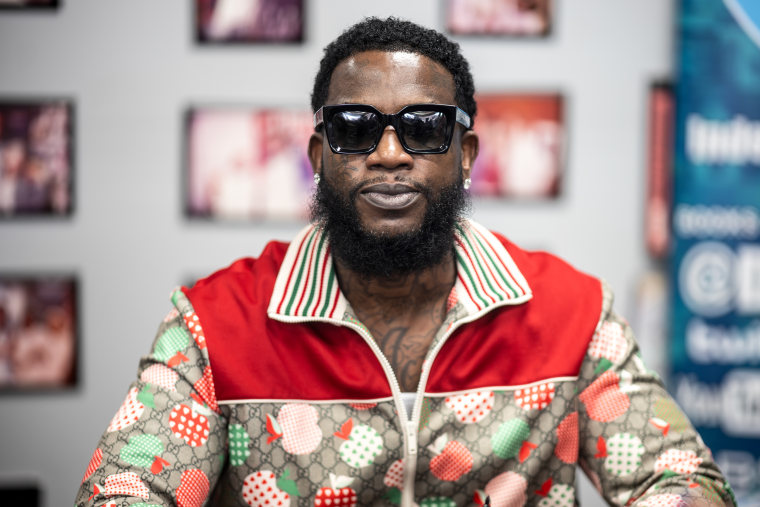 Gucci Mane is seated and wearing dark sunglasses.