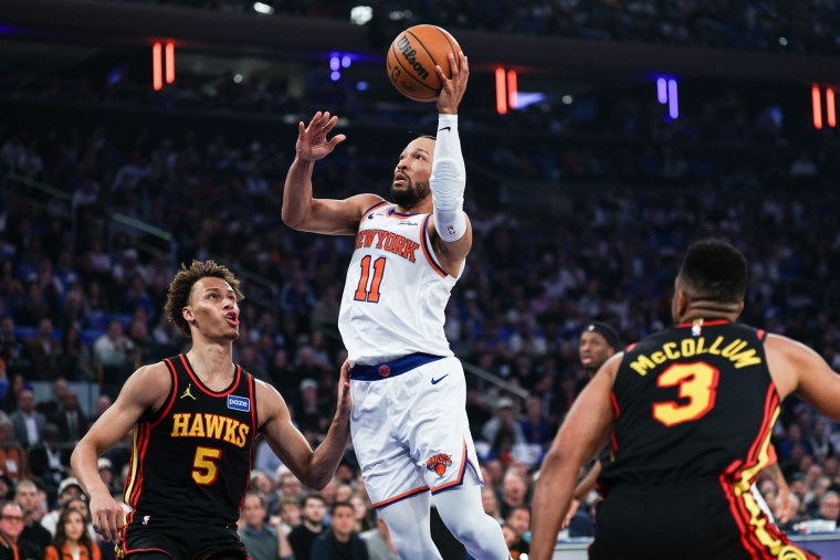 Jalen Brunson jumps to make a basket between two other players
