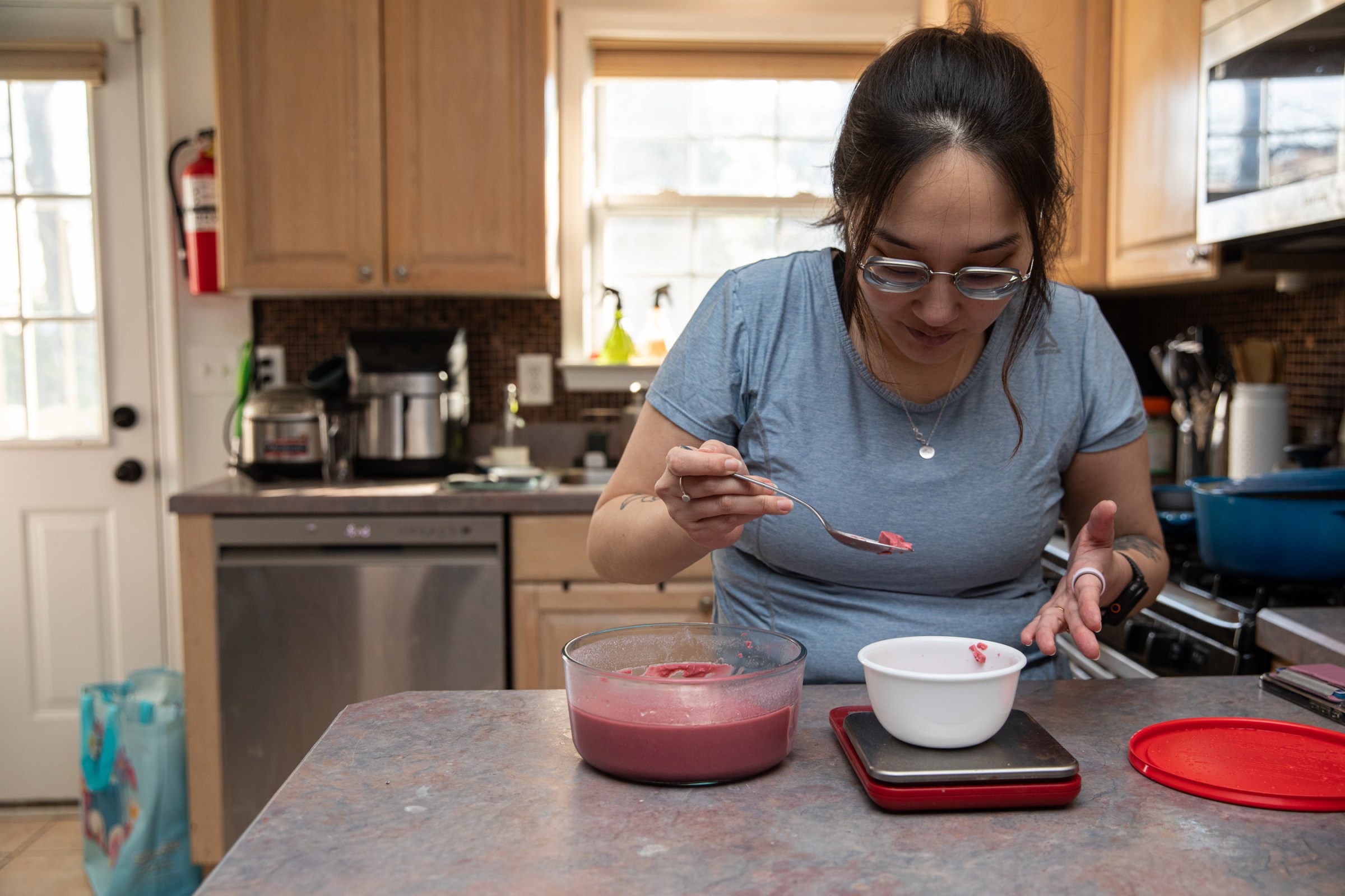 Senior reviewer Victoria Song measuring out a black cherry yogurt into a bowl on a food scale