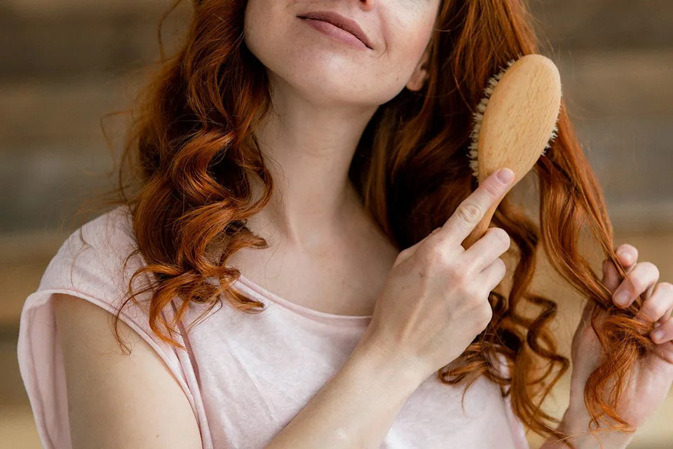 Stock image of a redheaded woman brushing her hairCredit: Getty