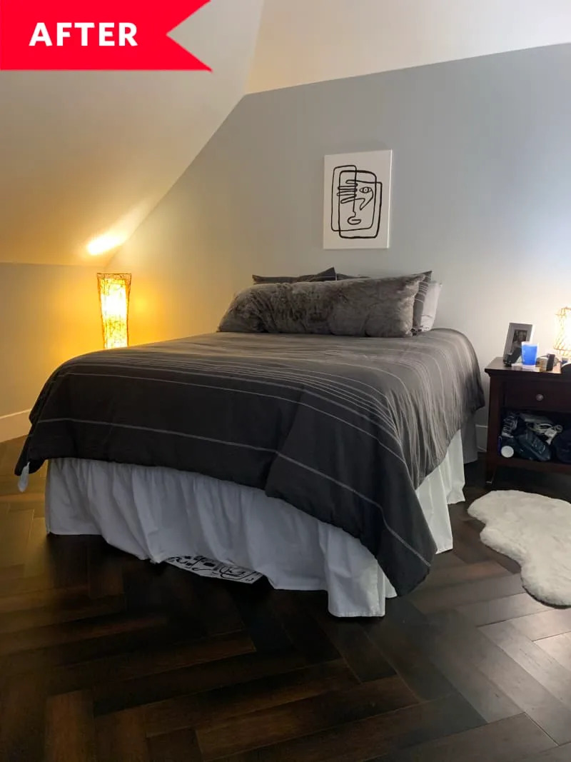 Cozy bedroom with a gray bedspread, abstract wall art, and warm lighting from a floor lamp.