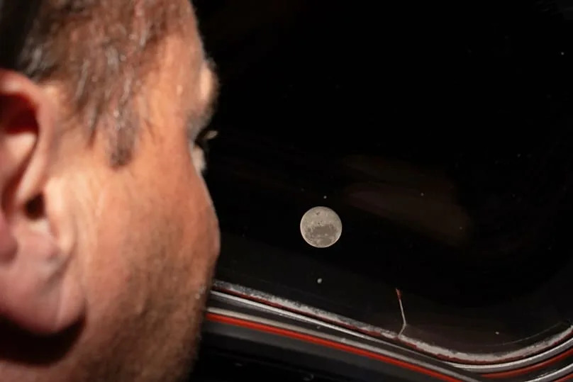 Artemis II commander and NASA astronaut Reid Wiseman looks out one of the Orion spacecraft's main cabin windows at the Moon ahead of the crew's lunar flyby on April 6, 2026.