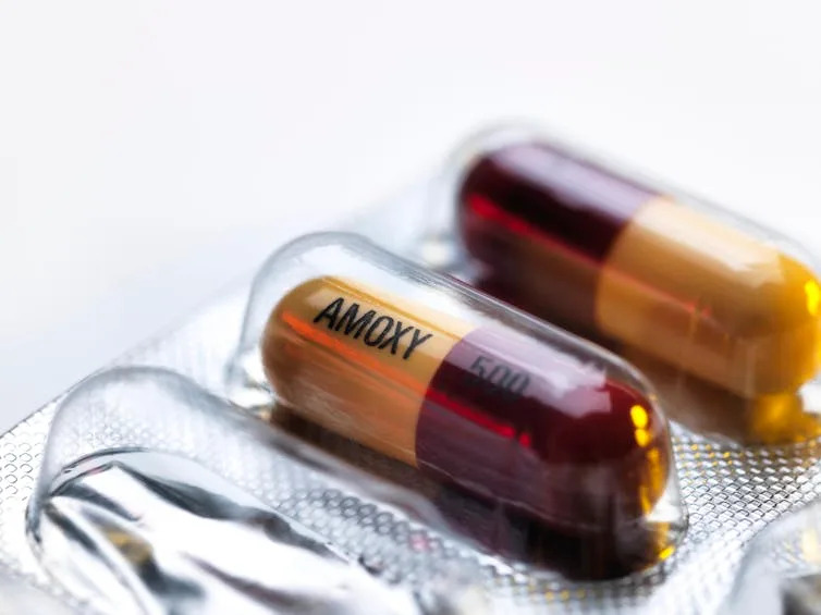 Close-up of two pill capsules inscribed AOMXY 500 in a blister packet