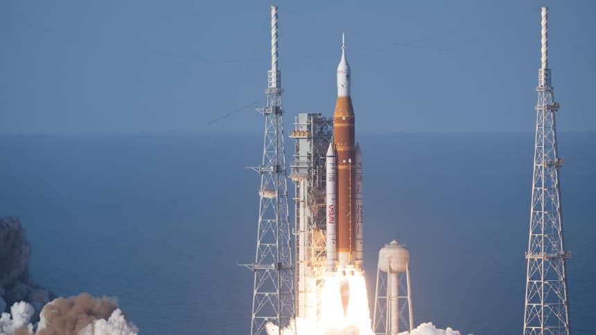 A rocket launches from a launch platform, trailing fire and smoke. 