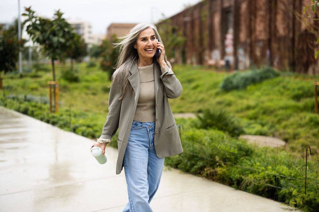 Portrait of a beautiful mature woman enjoying a walk in the park and talking on mobile phone