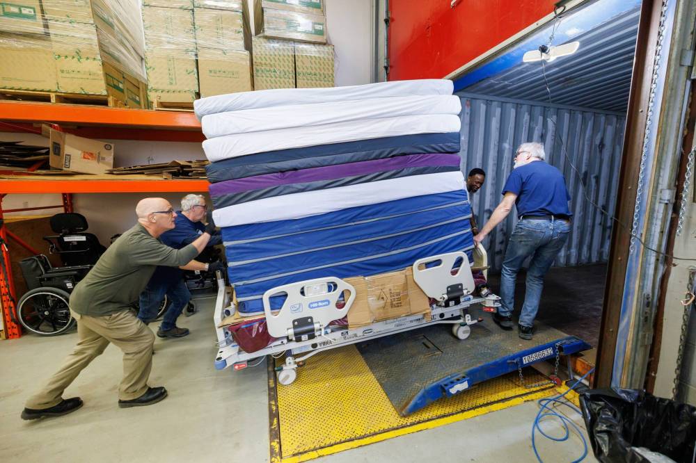 MIKE DEAL / FREE PRESS
Volunteers load a hospital bed piled high with mattresses into the shipping container.