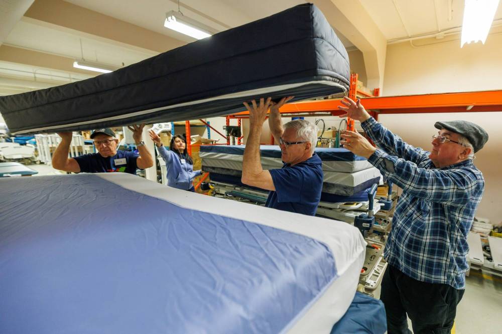 MIKE DEAL / FREE PRESS
Volunteers load a hospital bed with mattresses for the shipping container.