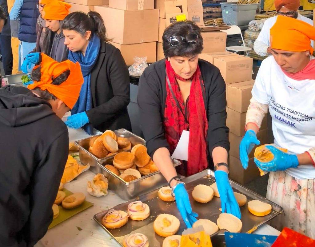 Raj Arneja (middle) and others prepare veggie burgers at the Nanak Foods stall during the 2025 Surrey Vaisakhi Parade in Newton. (Contibuted to Surrey Now-Leader)