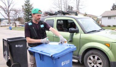 Oliver Berger attaches an Oops Card to a recycling bin in 100 Mile House. (Patrick Davies photo - 100 Mile Free Press)