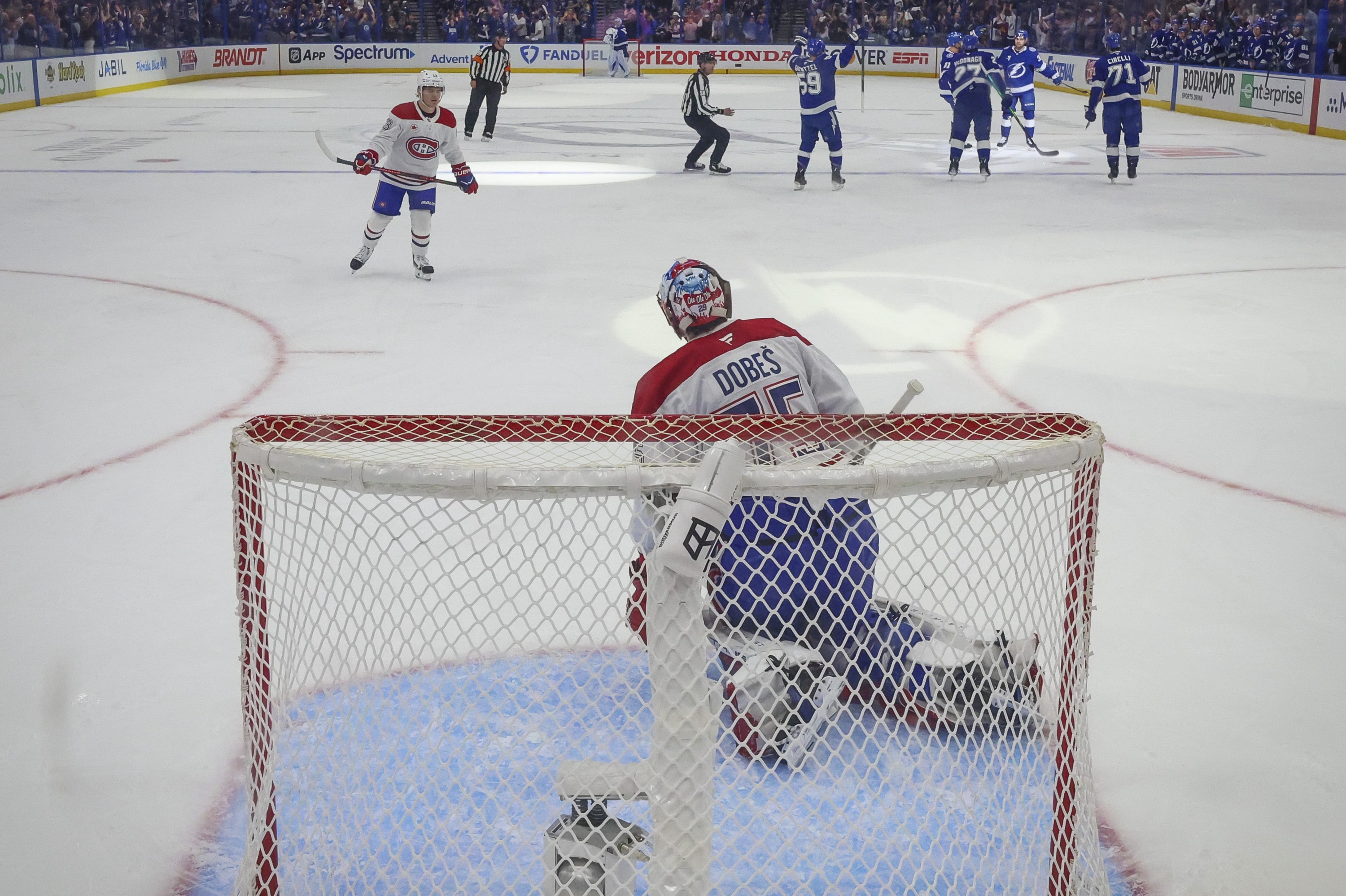Canadiens goaltender Jakub Dobes on his knees in the crease as Lightning players celebrate near the blue line