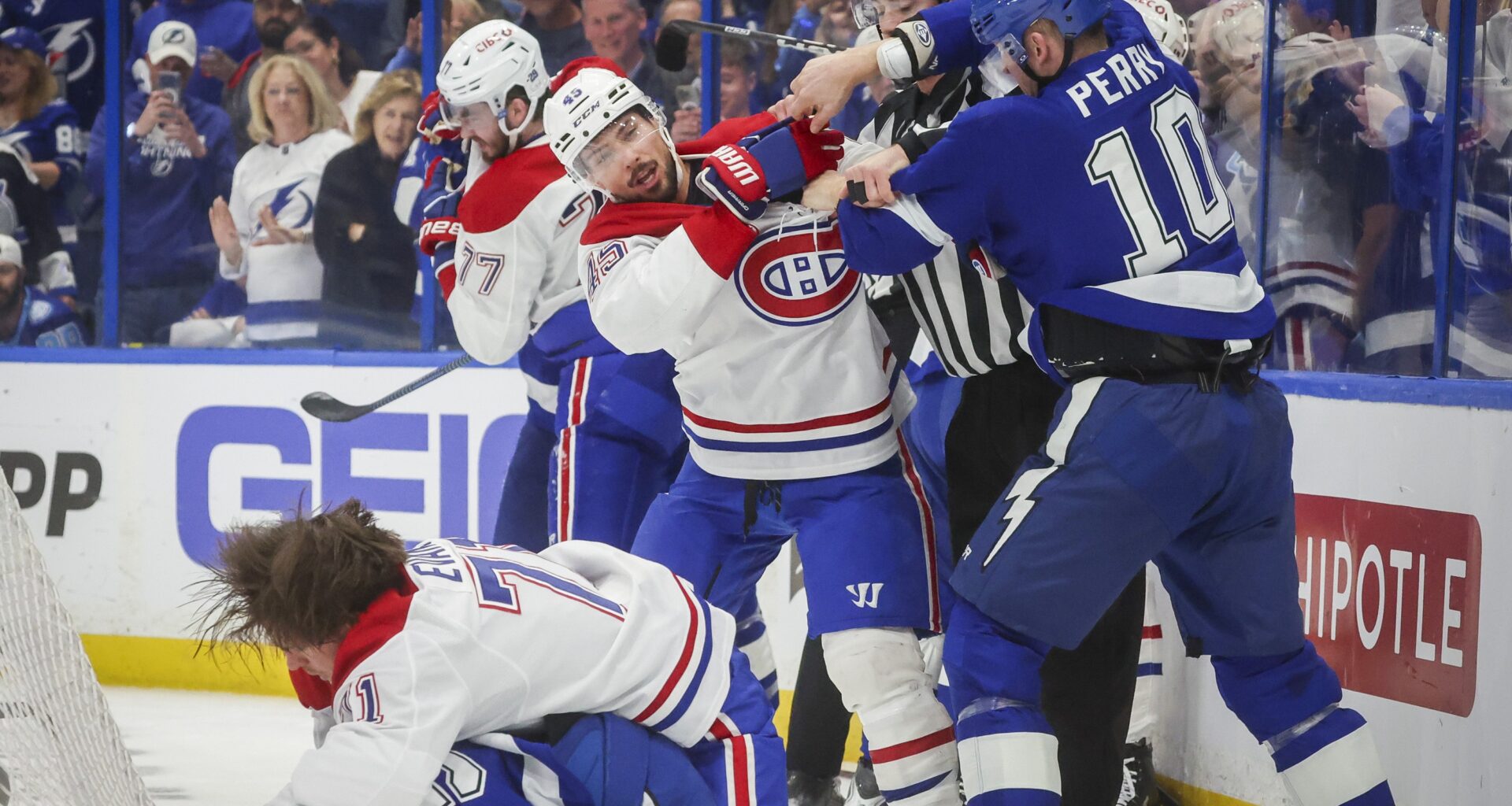 Canadiens and Lightning players fight each other behind the net.