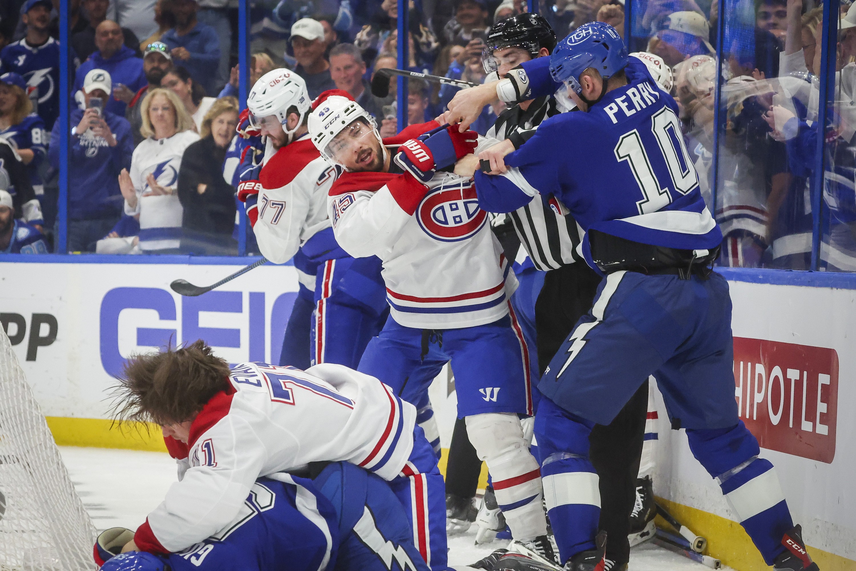 Canadiens and Lightning players fight each other behind the net.