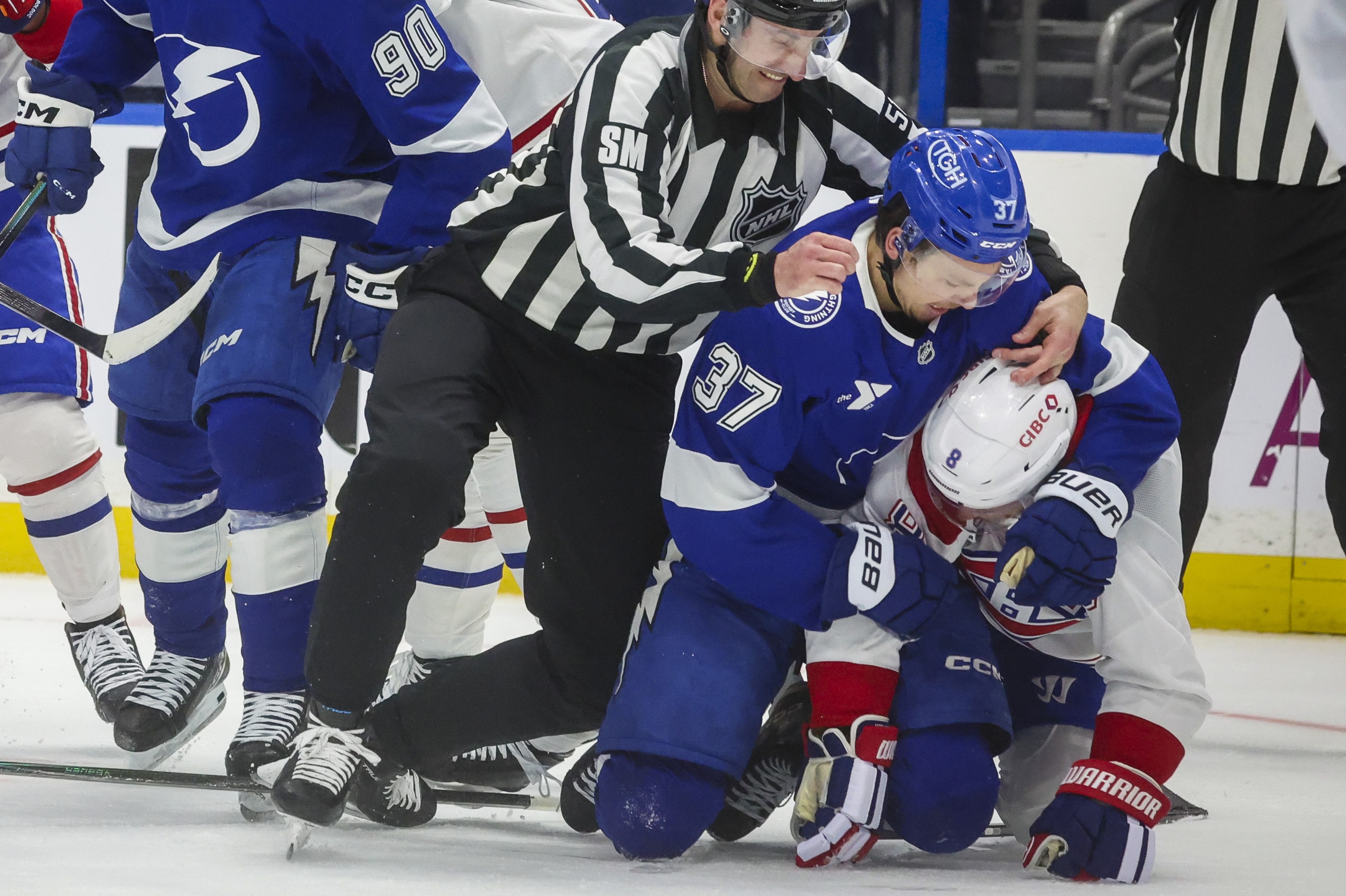 Tampa Bay Lightning's Yanni Gourde and Montreal Canadiens' Mike Matheson tangle as a linesman tries to intervene.