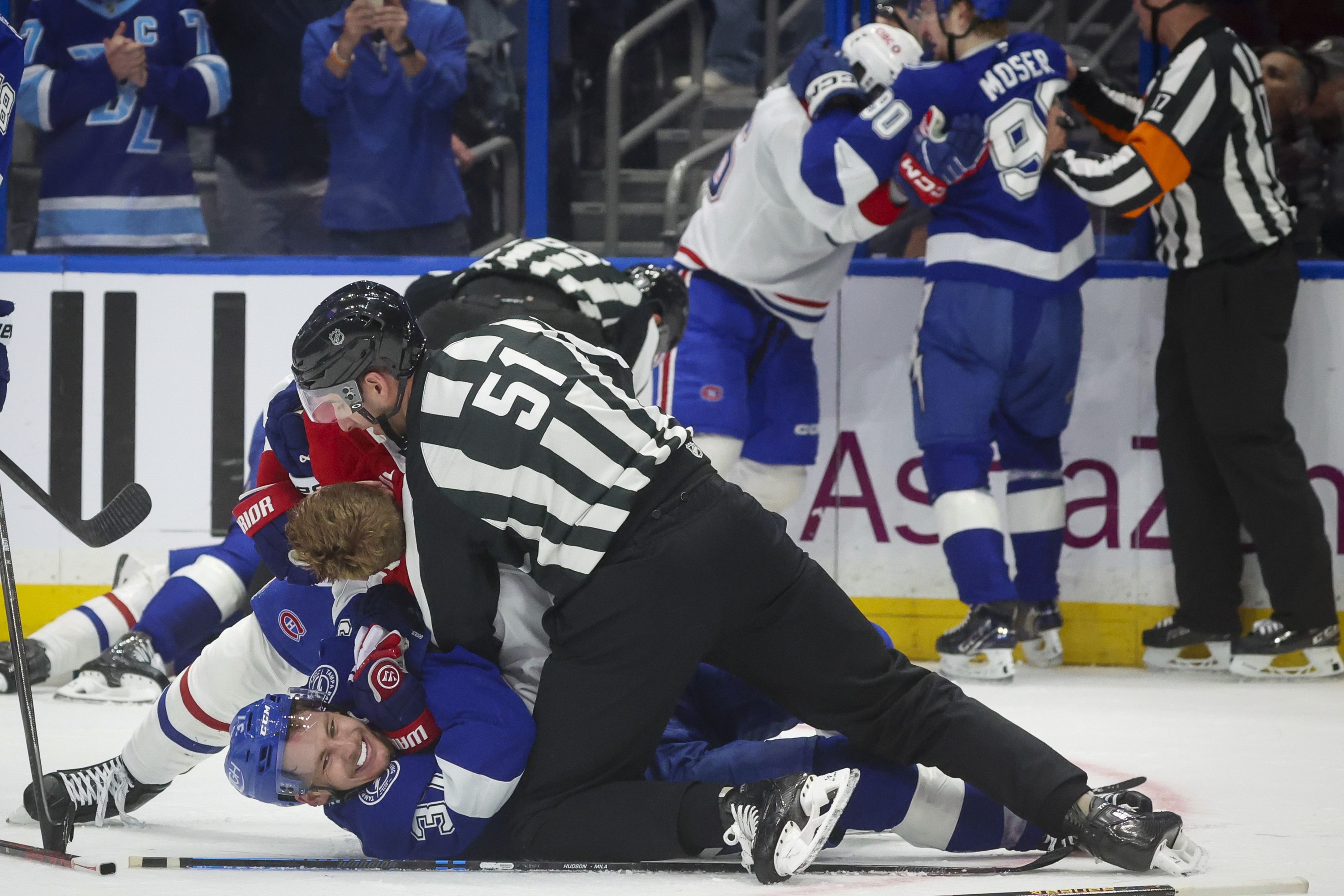 Tampa Bay Lightning centre Yanni Gourde (37), bottom, is held down by linesman Andrew Smith (51) as Canadiens defenceman Mike Matheson (8) falls on Gourde.