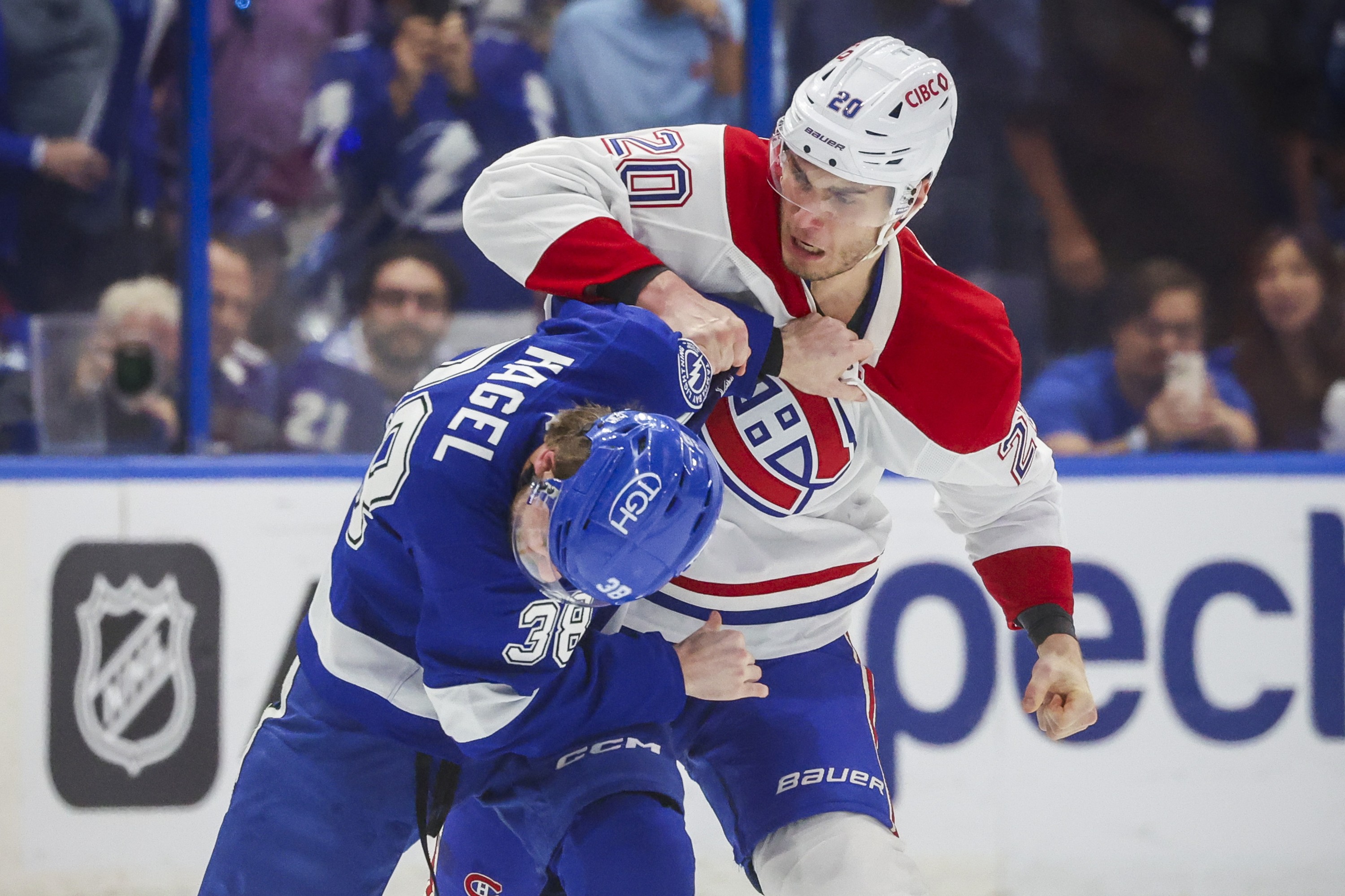 Canadiens' Juraj Slafkovsky prepares to throw a punch at Lightning's Brandon Hagel, who turns his head away while Slafkovsky grabs his arm.