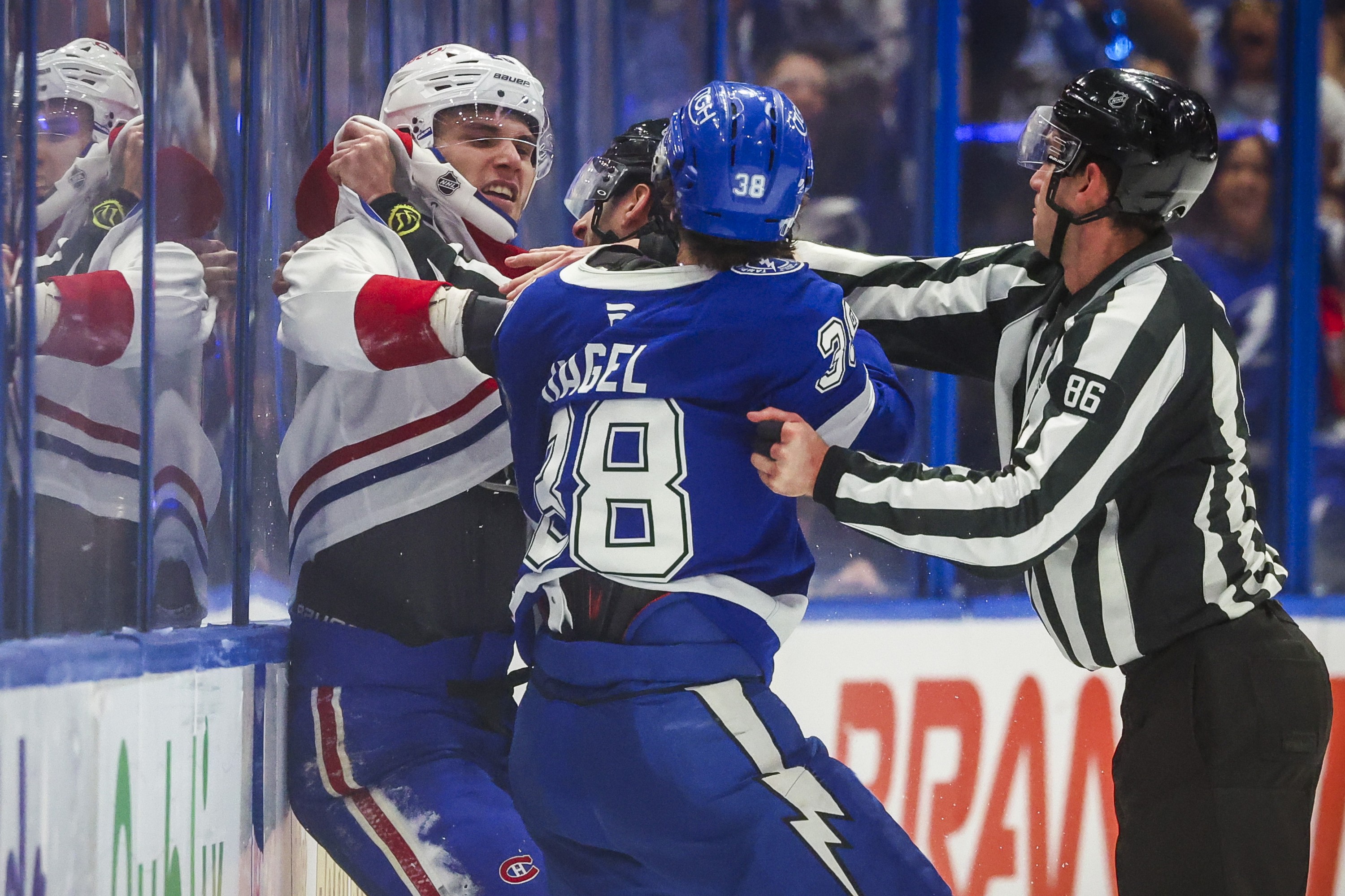 Linesman Jesse Marquis (86) attempts to break up a fight between Tampa Bay Lightning's Brandon Hagel and Canadiens' Juraj Slafkovsky