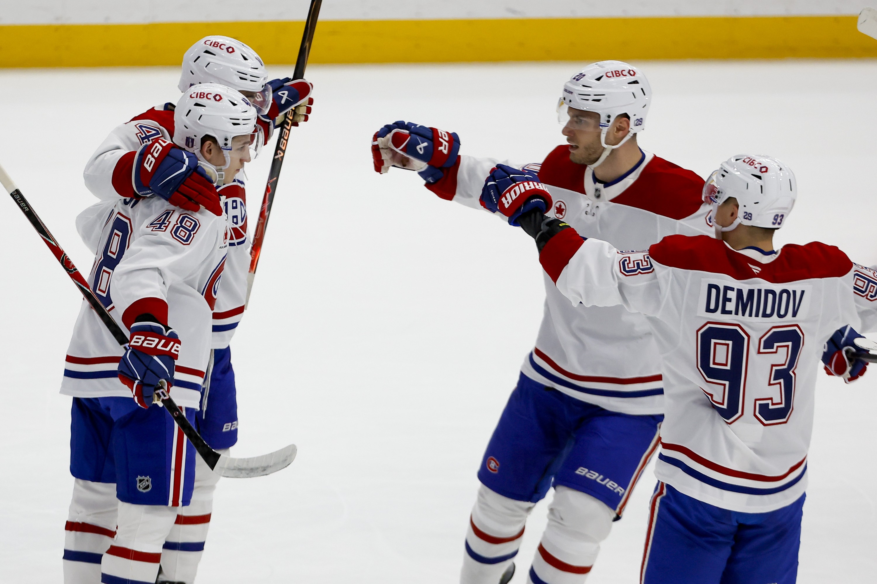 Four Canadiens players skate toward each other.