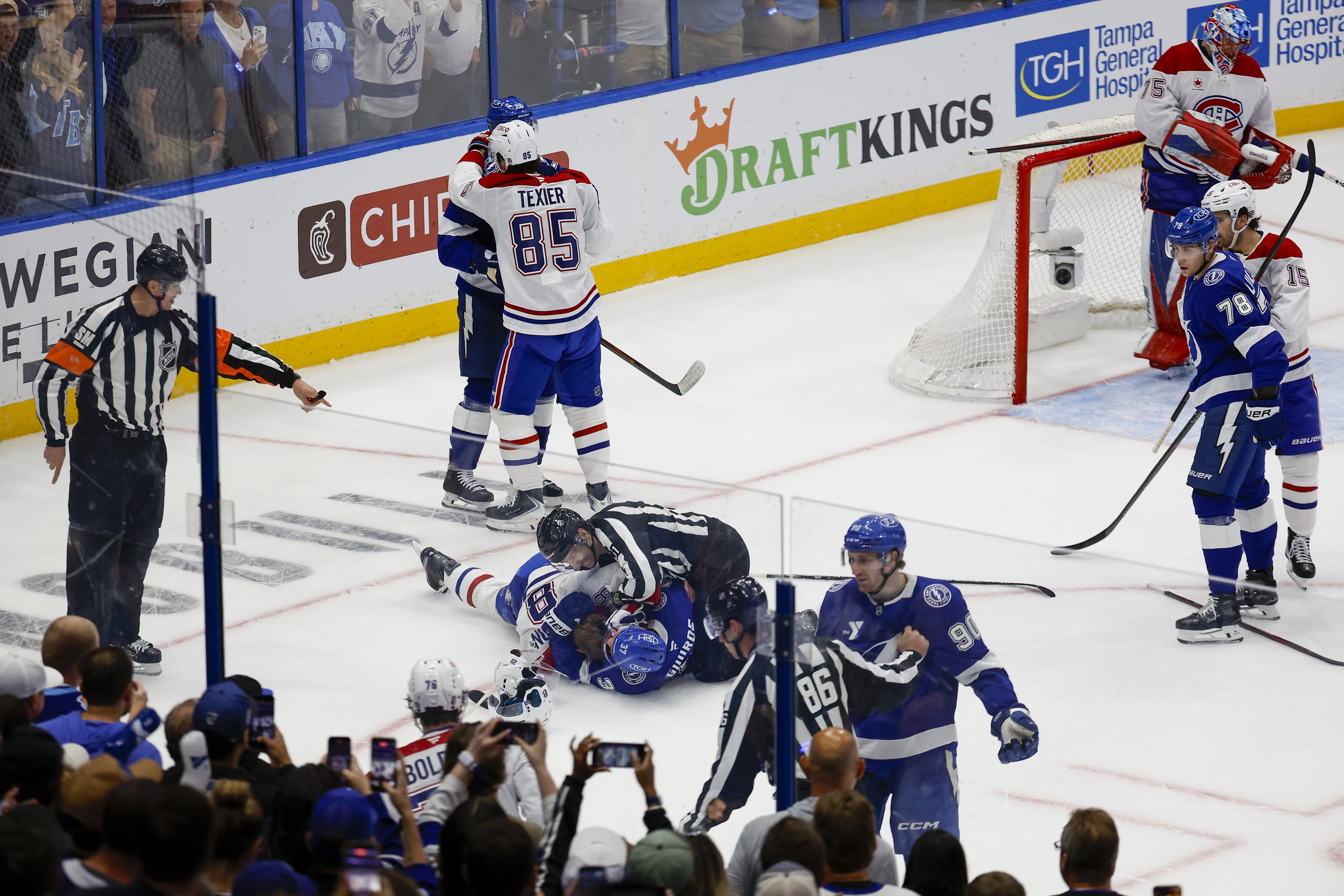 Fans record on their phones as Canadiens and Lightning players get into scuffles, including two lying on the ice with a linesman trying to intervene.