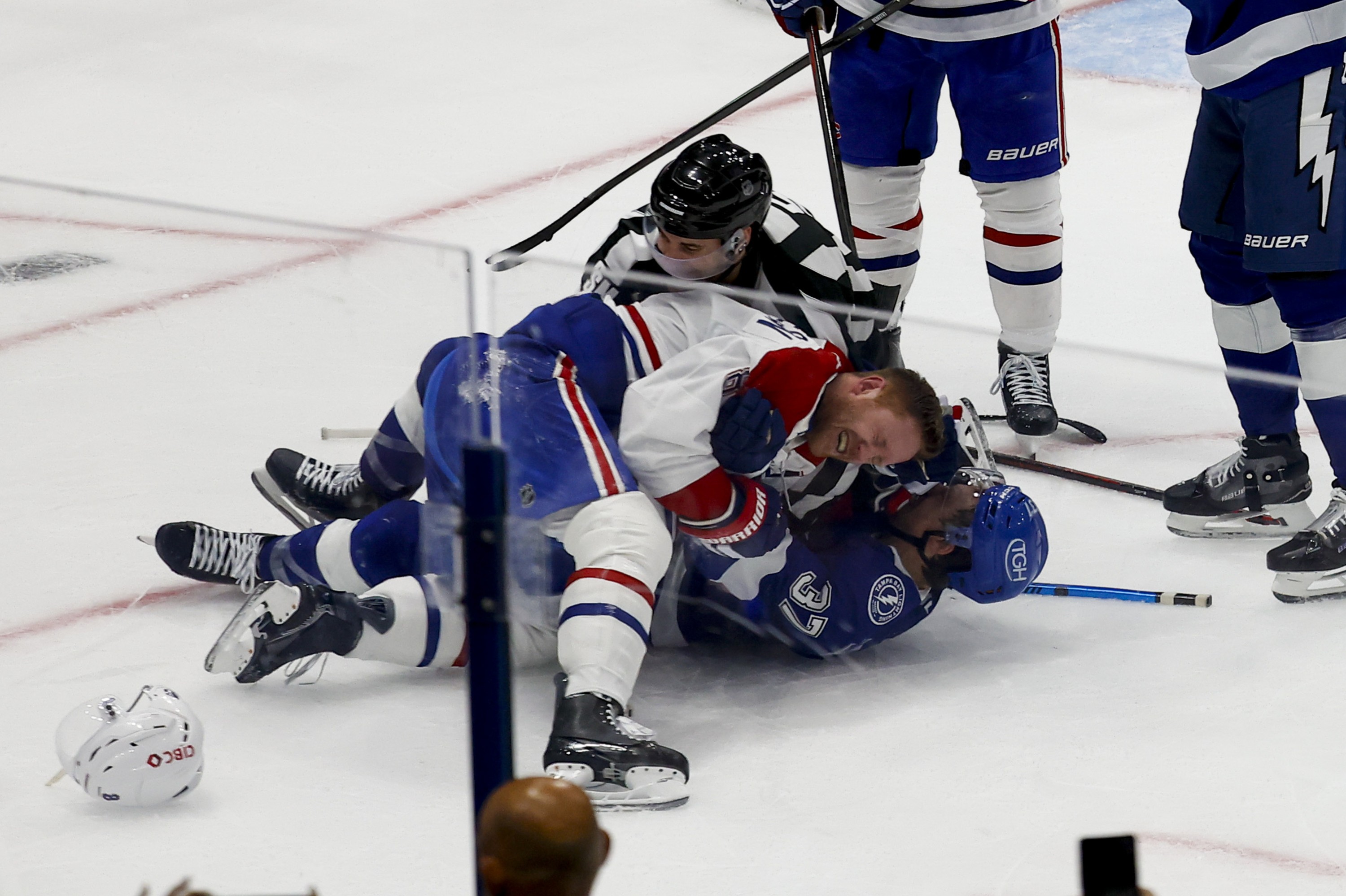 Canadiens' Mike Matheson on top of Lightning's Yanni Gourde lying on the ice.