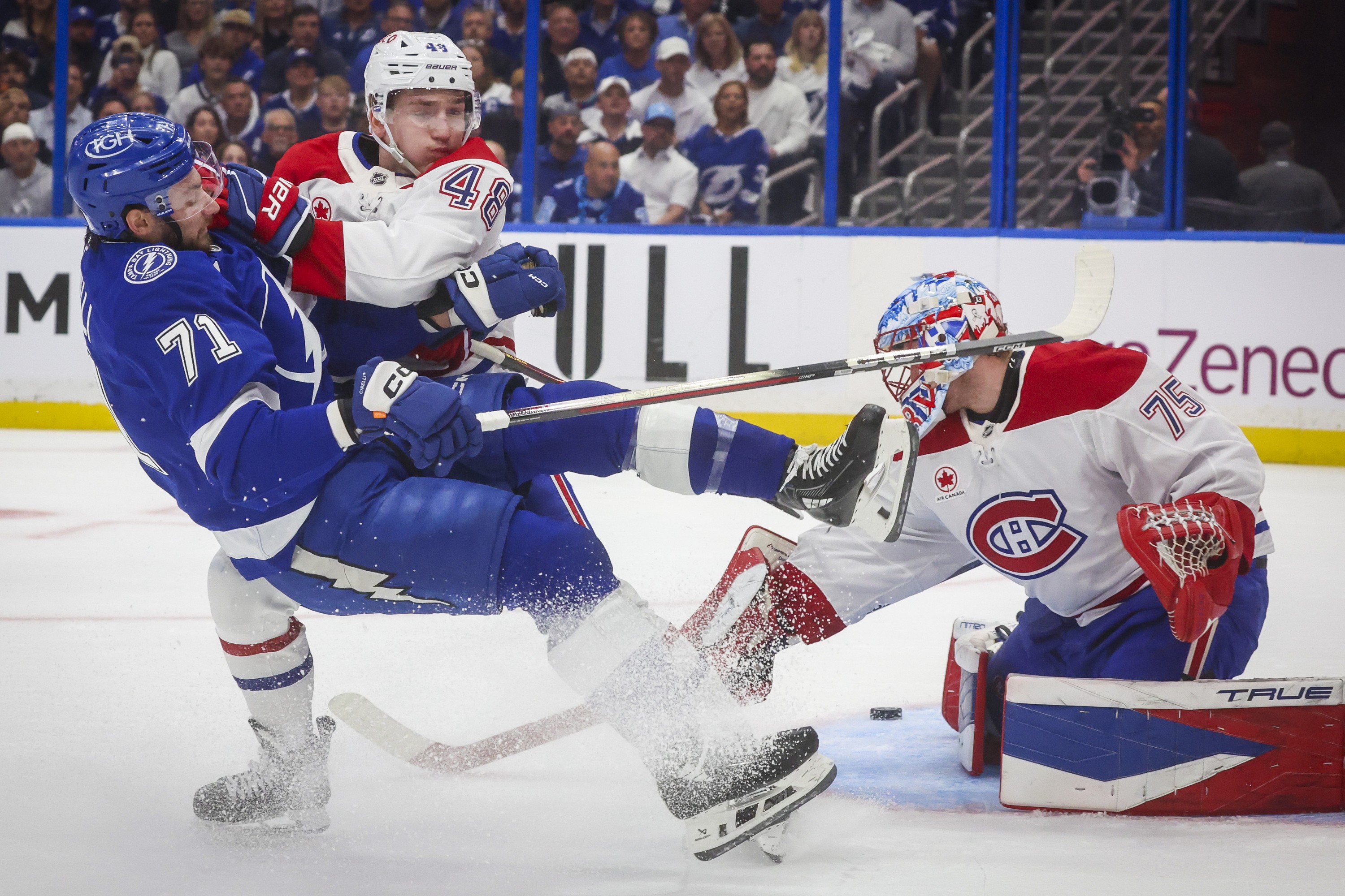 Tampa Bay Lightning centre Anthony Cirelli is knocked to the ice by Canadiens defenceman Lane Hutson in front of the Canadiens goaltender.