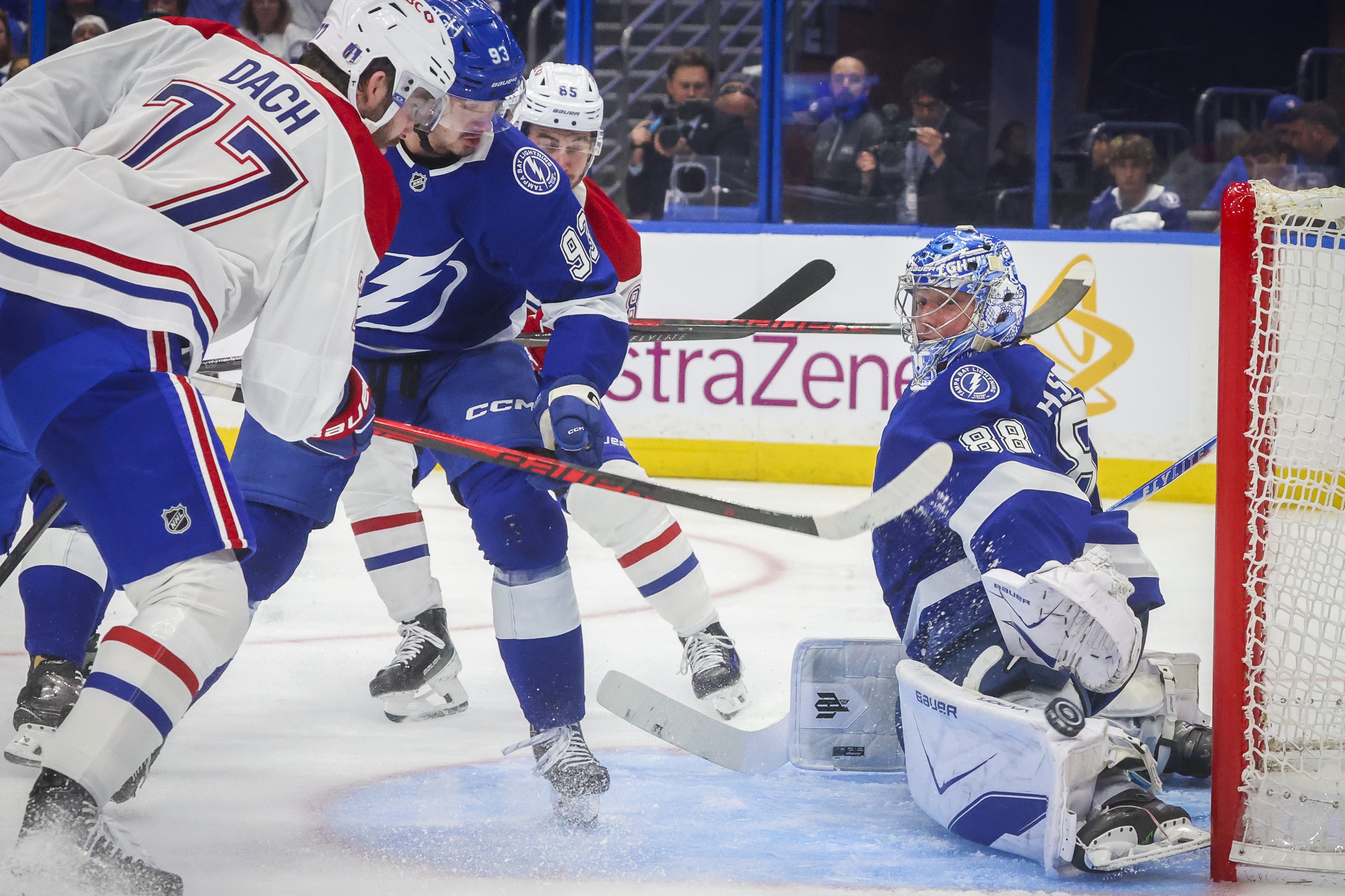The puck flies by the glove of Tampa Bay Lightning goaltender Andrei Vasilevskiy as Canadiens' Kirby Dach follows through on a shot just outside the crease.