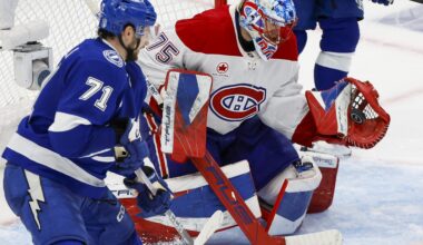 The puck is in Jakub Dobes's glove as Lightning's Anthony Cirelli looks on.