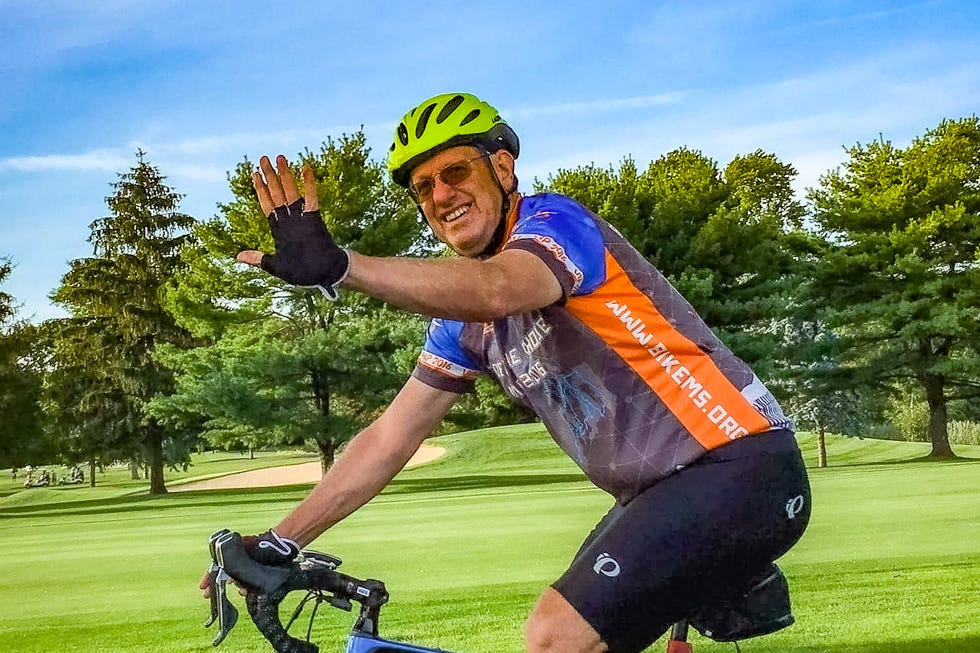 Cyclist waving while riding on a path. Cyclist waving while riding on a path.