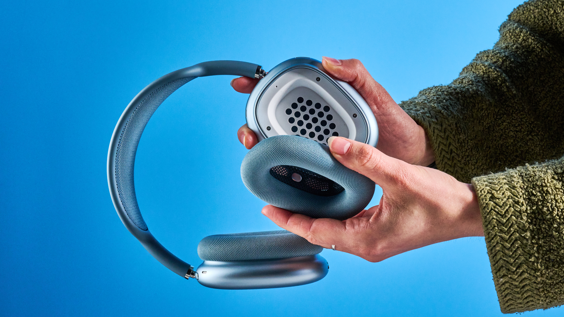 the apple airpods max 2 in blue photographed against a blue tom's guide background, showing the mesh headband, anodized aluminum ear cups, carry case, and controls