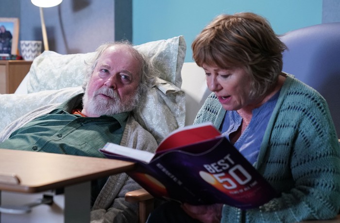 Julie reads to Nigel in his care home in a scene from EastEnders